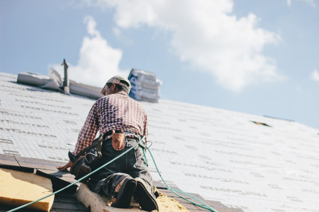 roofer adding shingles to the roof of a house utc